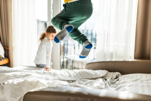 Jumping on the bed Beautiful boy and girl jumping on the bed in the morning. child candid indoors lifestyles stock pictures, royalty-free photos & images