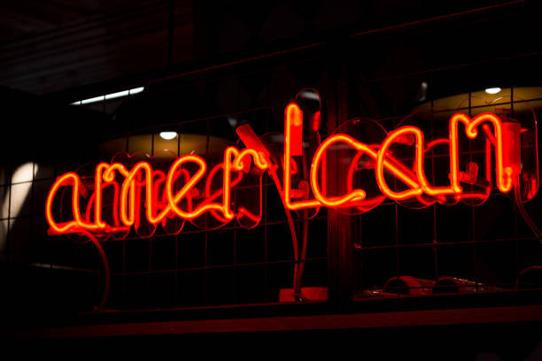 istock Glowing Neon red sign AMERICAN and blurred lights on black background. 1301382988