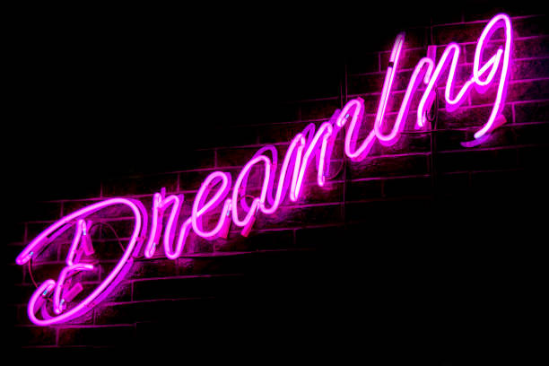 istock Glowing Purple Neon Inscription DREAMING 1301383060