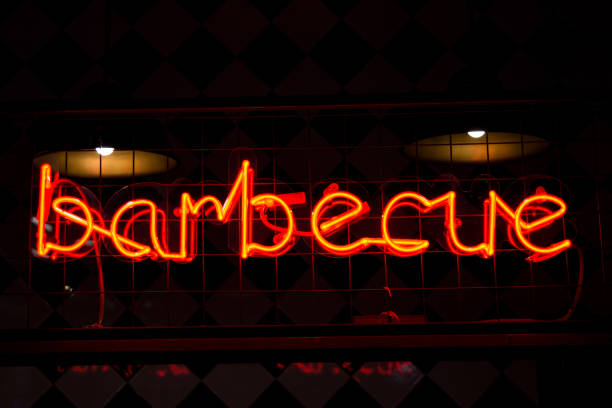 istock Glowing Neon red sign BARBECUE and blurred lights on black background. 1301383777