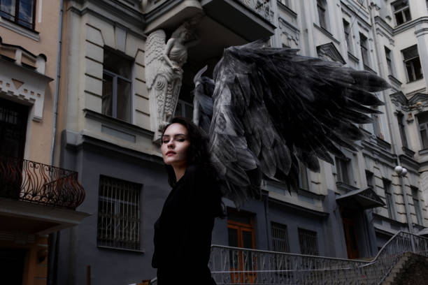 vrouwelijke engel met donkere vleugels die lopen - engelenpak stockfoto's en -beelden