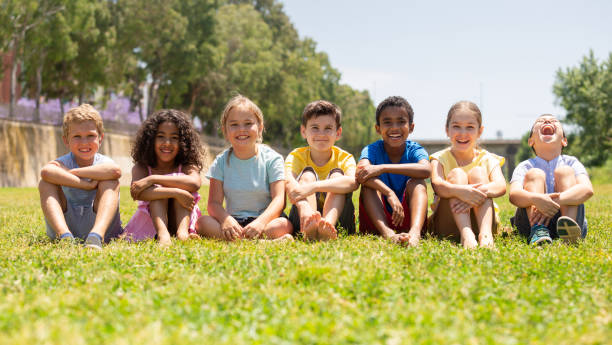 istock Happy children sitting on the green grass on day 1301390445