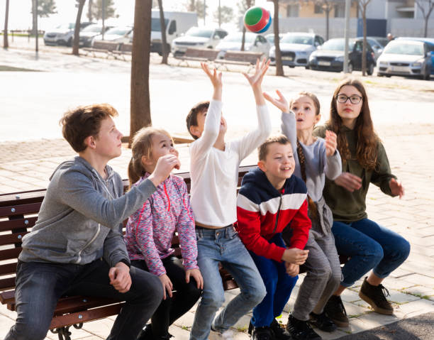 istock Children sitting on bench and playing ball 1301391980