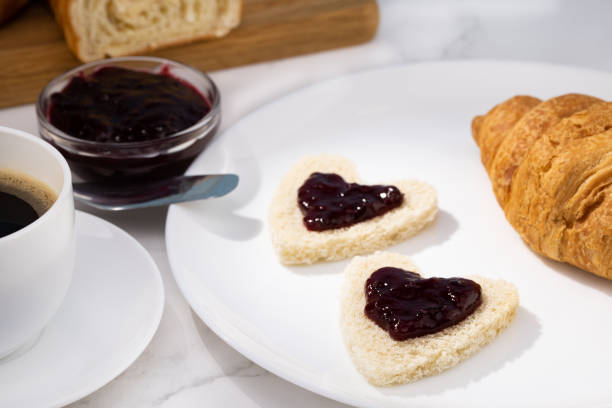 istock fresh croissants with jam and coffee on light background. Heart shaped toast breakfast for Valentine's Day 1301393470
