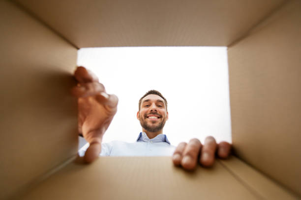 istock smiling man taking something out of parcel box 1301393787
