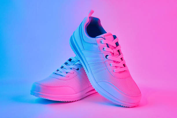Fashion white sneakers in neon light. Sport shoes for training in the gym. Creative minimalism. 90s concept. Fashion white sneakers in neon light. Sport shoes for training in the gym. Creative minimalism. sports shoe photos stock pictures, royalty-free photos & images