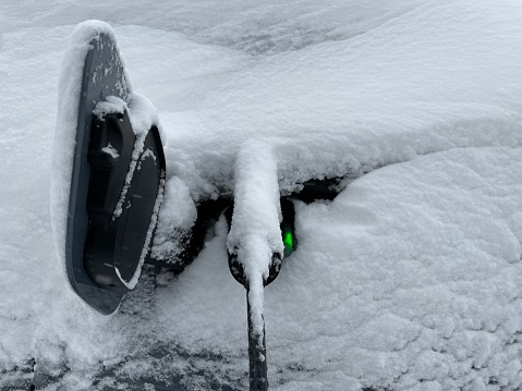 An electric car is charging in the snow.