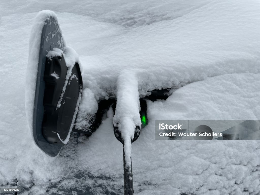 Electric car charging An electric car is charging in the snow. Electric Car Stock Photo
