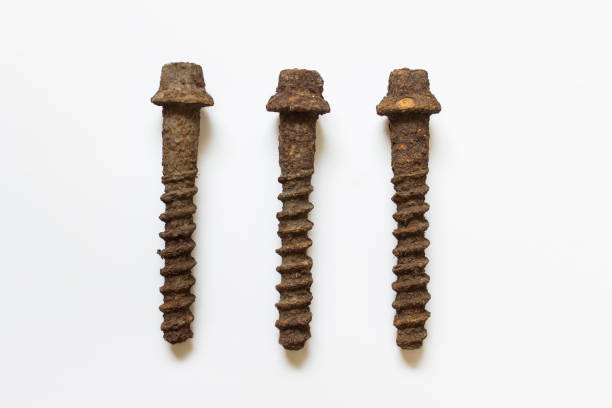 Large long rusted corroded screws used for railroad rails attachment on white background.