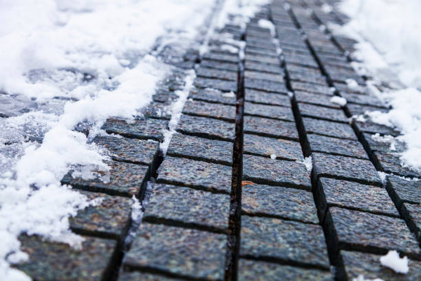 Stone path in the park in the snow close-up. Winter in the city.