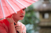 赤い日本の傘を持つ着物を着た若い女性
