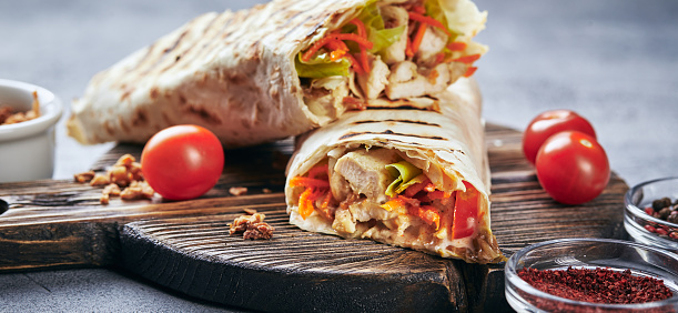 Eastern traditional shawarma with chicken and vegetables, Doner Kebab with sauces on wooden cutting board. Fast food. Eastern food.