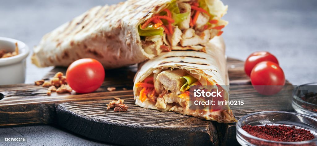 Eastern traditional shawarma with sauces Eastern traditional shawarma with chicken and vegetables, Doner Kebab with sauces on wooden cutting board. Fast food. Eastern food. Wrapping Paper Stock Photo