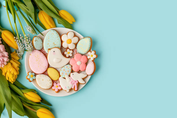 istock Easter gingerbread with icing on plate, seasonal flowers on blue, festive Easter background web banner, copy space. Easter card with traditional treats. Sweet Easter concept, greeting card 1301400382