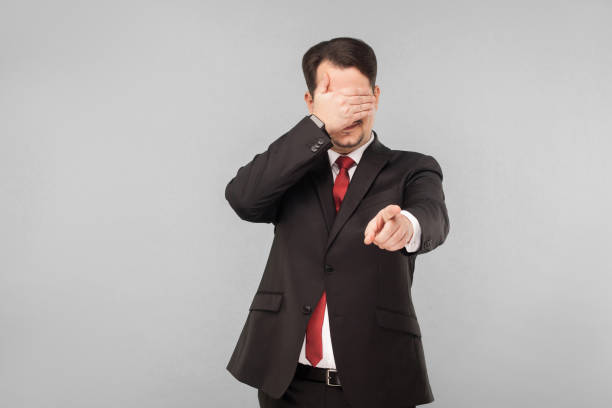istock Man in suit closed eyes and pointing finger at camera 1301400489