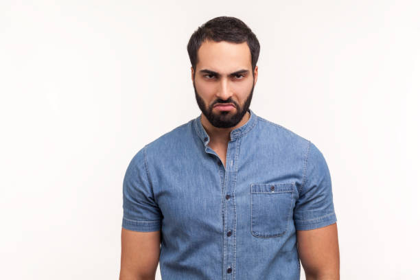 istock Depressed sorrowful bearded man in blue shirt looking at camera with unhappy sad expression, tired of being lonely 1301401046