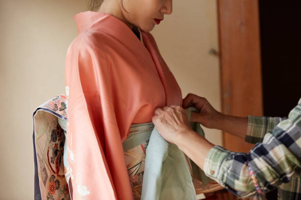 A young woman getting dressed in a kimono