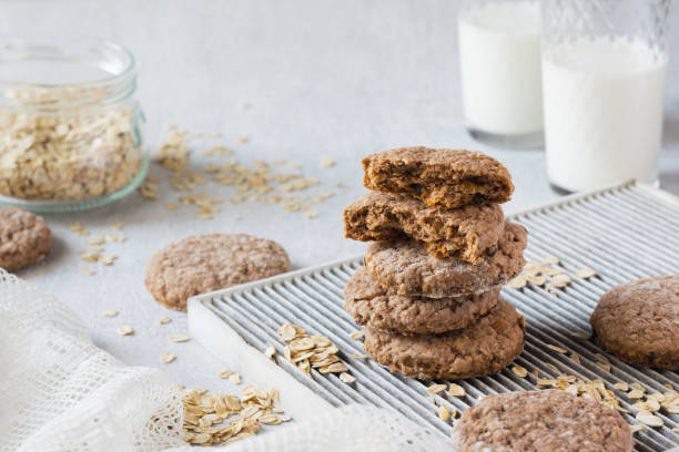 pila di biscotti di farina d'avena fatti in casa con fiocchi d'avena e due bicchieri di latte su sfondo grigio. messa a fuoco selettiva, orientamento horisontal - oat oatmeal isolated stack foto e immagini stock