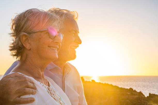 couple of two cute seniors together enjoying summer and having fun at the beach looking at the sea or ocean with sunset - mature people having a good lifestyle couple of two cute seniors together enjoying summer and having fun at the beach looking at the sea or ocean with sunset - mature people having a good lifestyle over 80 stock pictures, royalty-free photos & images