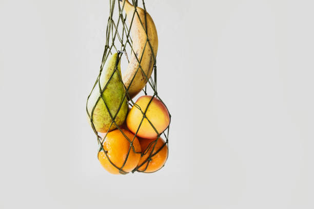 istock fresh real fruits without retouching in mesh string bag on white background, reasonable reusable use of things, the habit of taking care of environment, selective focus 1301402296