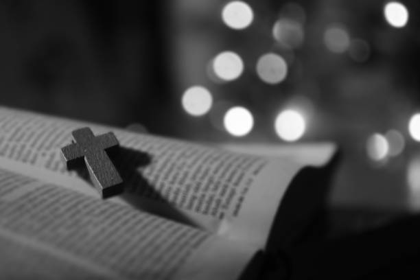 istock Religious cross crucifix on open bible book page in black and white background. 1301402850