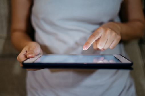 Close up of hand of an Asian woman using a digital tablet