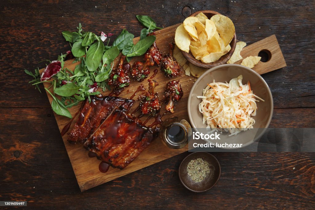 BBQ Lollipop Chicken Wings and Spicy Glazed Pork Ribs BBQ lollipop chicken wings with spicy BBQ glaze. Spicy glazed pork ribs. Flat lay top-down composition on dark background. Barbecue - Meal Stock Photo