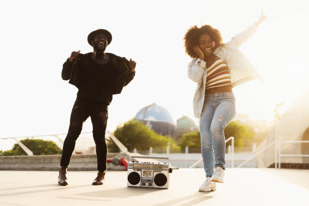 Young Afro friends dancing outdoor while listening to music with wireless headphones and vintage boombox Young Afro friends dancing outdoor while listening to music with wireless headphones and vintage boombox street friends stock pictures, royalty-free photos & images