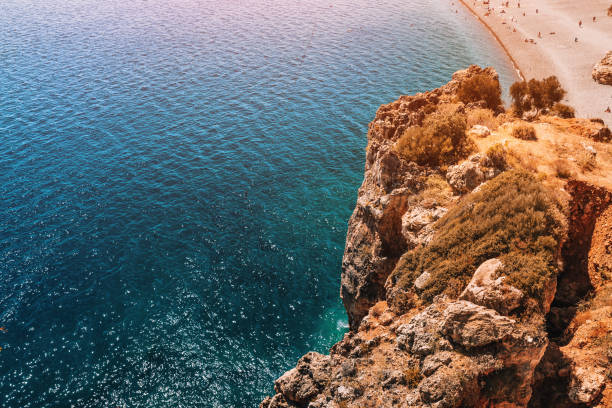 Rocky cliff with pebble beach aerial drone view. Sea coastline concept