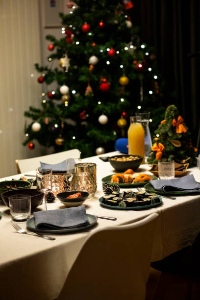istock Christmas dinner table setting with linen tablecloth, napkins, sushi, salmon disk, Christmas tree. Evening, night table set for four. 1301407785