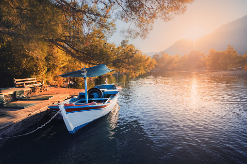 Panoramic landscape with a river flowing into the sea and a motor boat moored at the pier with Mount Tahtali in the background. Paradise vacation and tourism in Tekirova, Turkey