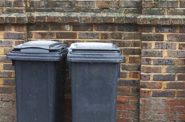 Wheelie Bins Wheelie bins on a pavement waiting for rubbish collection, UK. overflowing trash dumpster stock pictures, royalty-free photos & images