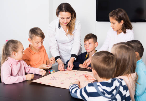 istock Elementary age concentrated children at table with board game and dice 1301411389