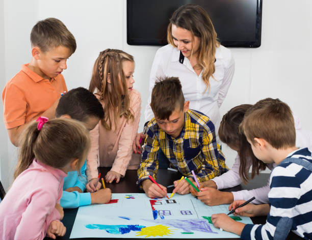 istock Children with teacher drawing together in classroom 1301411391