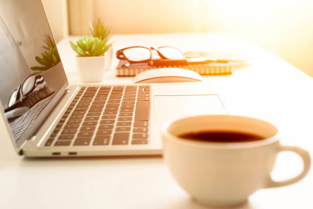 istock soft focus of keyboard laptop computer on desk table office, coffee cup and notebook, glasses. Business and finance concept. Workplace with morning sunlight from the window with copy space. 1301412317