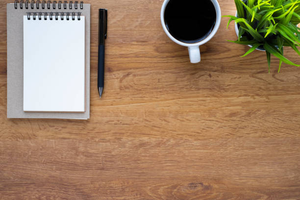 istock Top view of open school notebook with blank pages, coffee cup and pen for taking write notes on table background. Flat lay, creative workspace office. Business-education concept with copy space. 1301412318