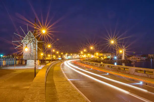 Photo of Old windmill and light trails motion of the passing by cars.