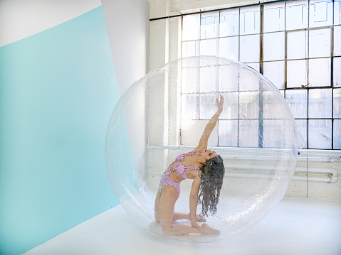 Female circus performer inside inflated plastic bubble during practice performance.