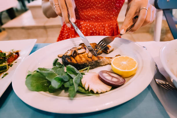 istock Woman eating fried salmon steak in restaurant. 1301418710