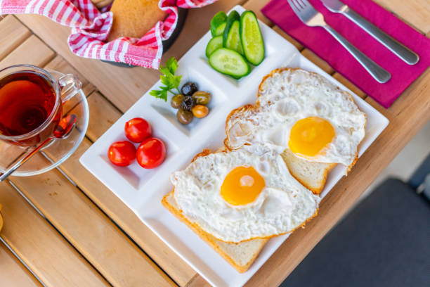 Fried eggs sunny side up on bread with side dishes.