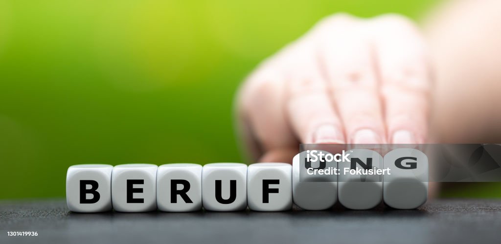 Hand turns dice and changes the German word "Beruf" (job) to "Berufung" (profession). Dream Job Stock Photo