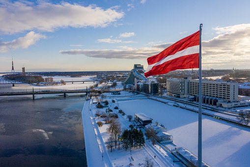 Panorama view of the Riga city with a big Latvian flag by the river Daugava. Latvian spirit.