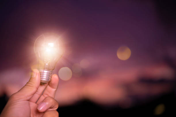 istock concept power energy in nature. hand holding lightbulb with solar, sunset power concept 1301423377