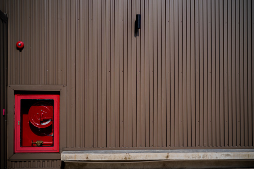 Fire hose hanging on the wall in the corridor, Electric alarm jingle