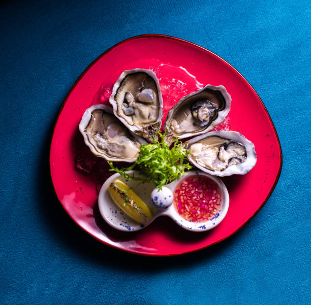 istock Fresh oysters in a red plate with ice and lemon 1301423764