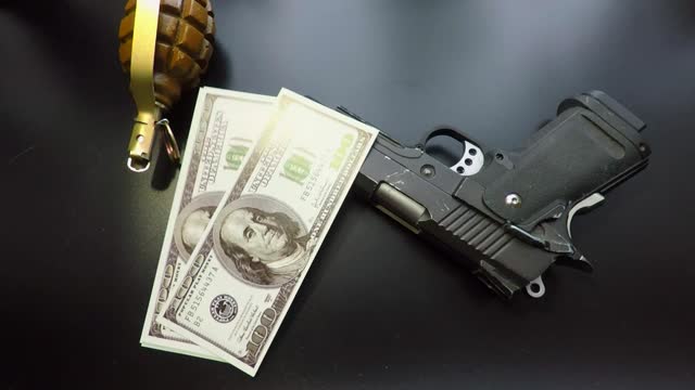 black background a pistol dollars and a hand grenade