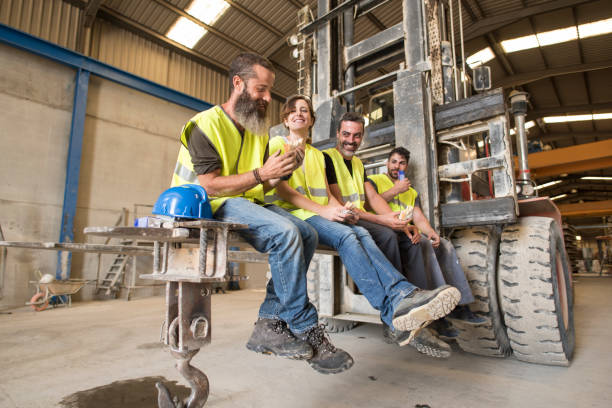 Construction workers take a break snacking on the blades of a giant forklift