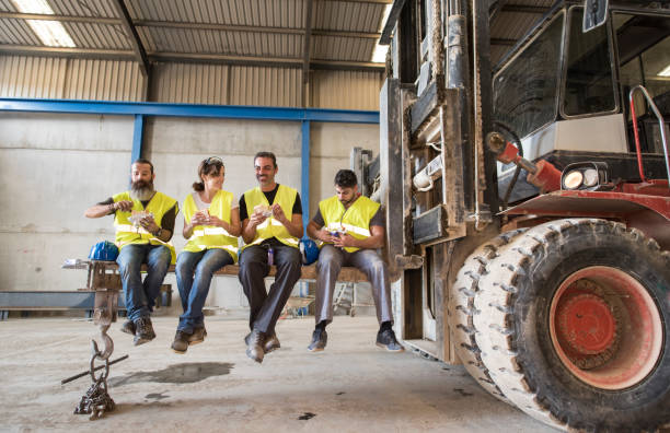 Construction workers take a break snacking on the blades of a giant forklift stock photo
