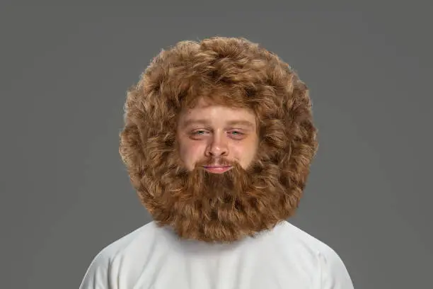 Photo of Portrait of young very hairy man isolated over grey background.