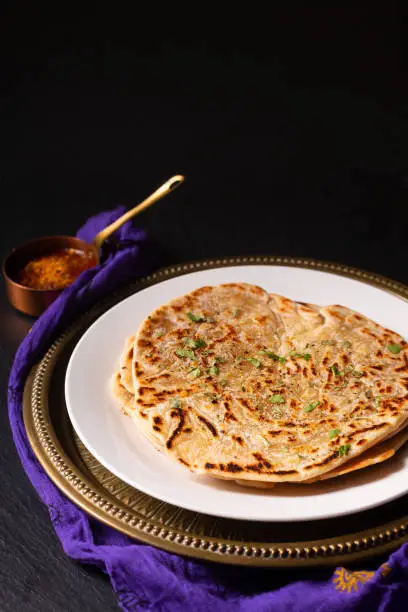 Photo of Food concept spot focus homemade Paratha, Parotta or Porotta layered flatbread  on black background with copy space